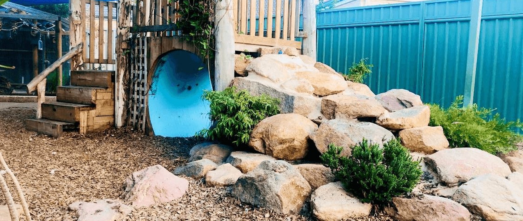 Our nature-based outdoor play space with shade sails and rock garden